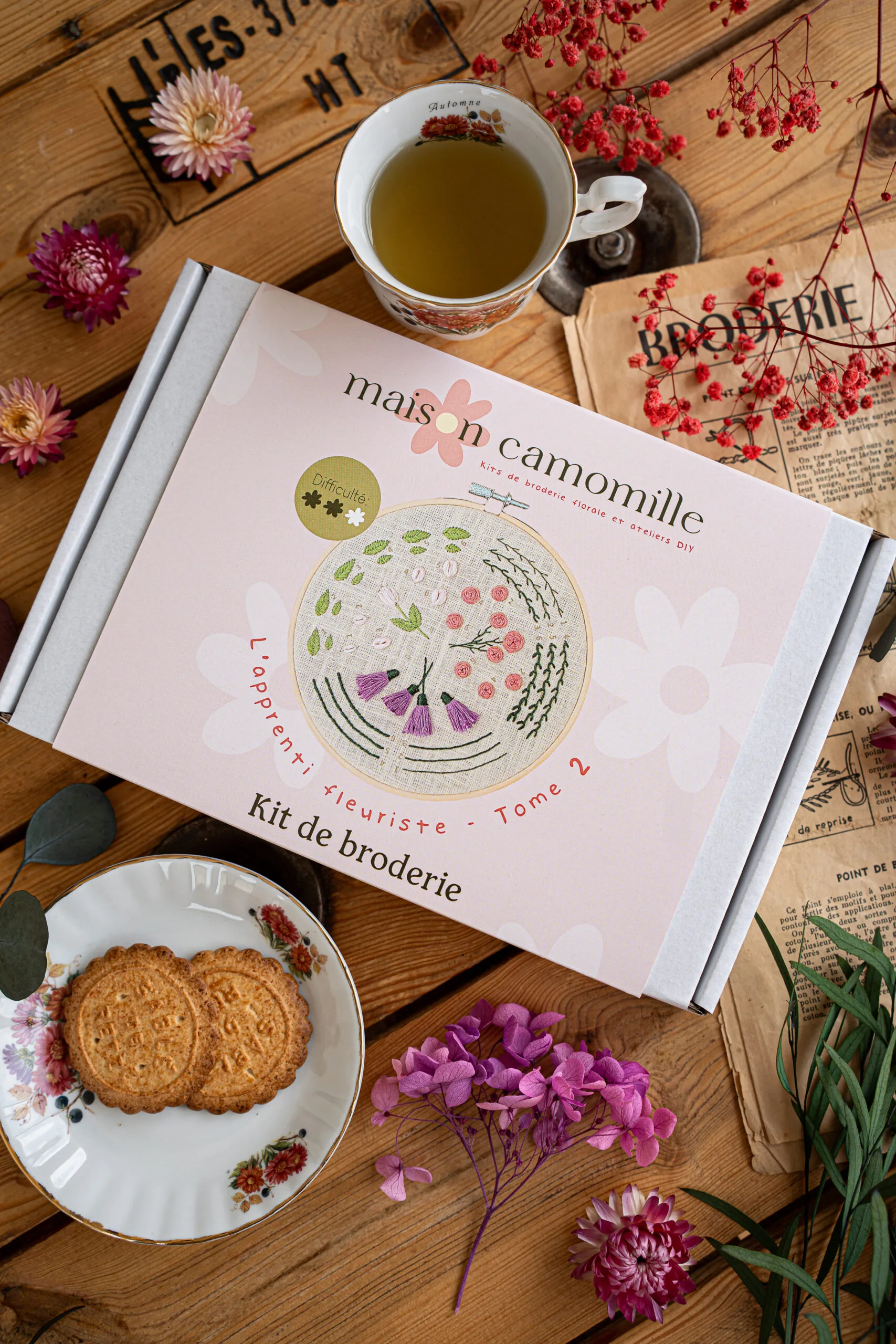 Kit broderie "L'apprenti fleuriste" Tome 2 dans son emballage avec révélation du modèle à broder sur son packaging
