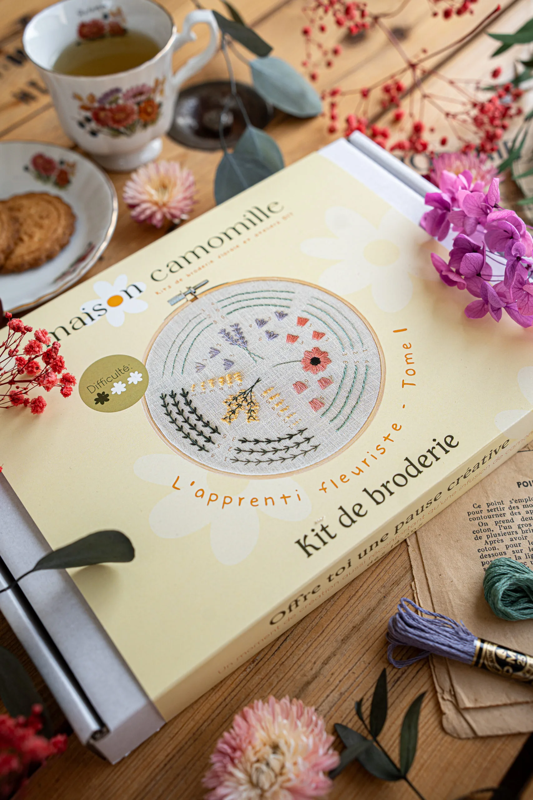 Kit broderie "L'apprenti fleuriste" Tome 1 dans son emballage avec revelation du modèle sur le packaging