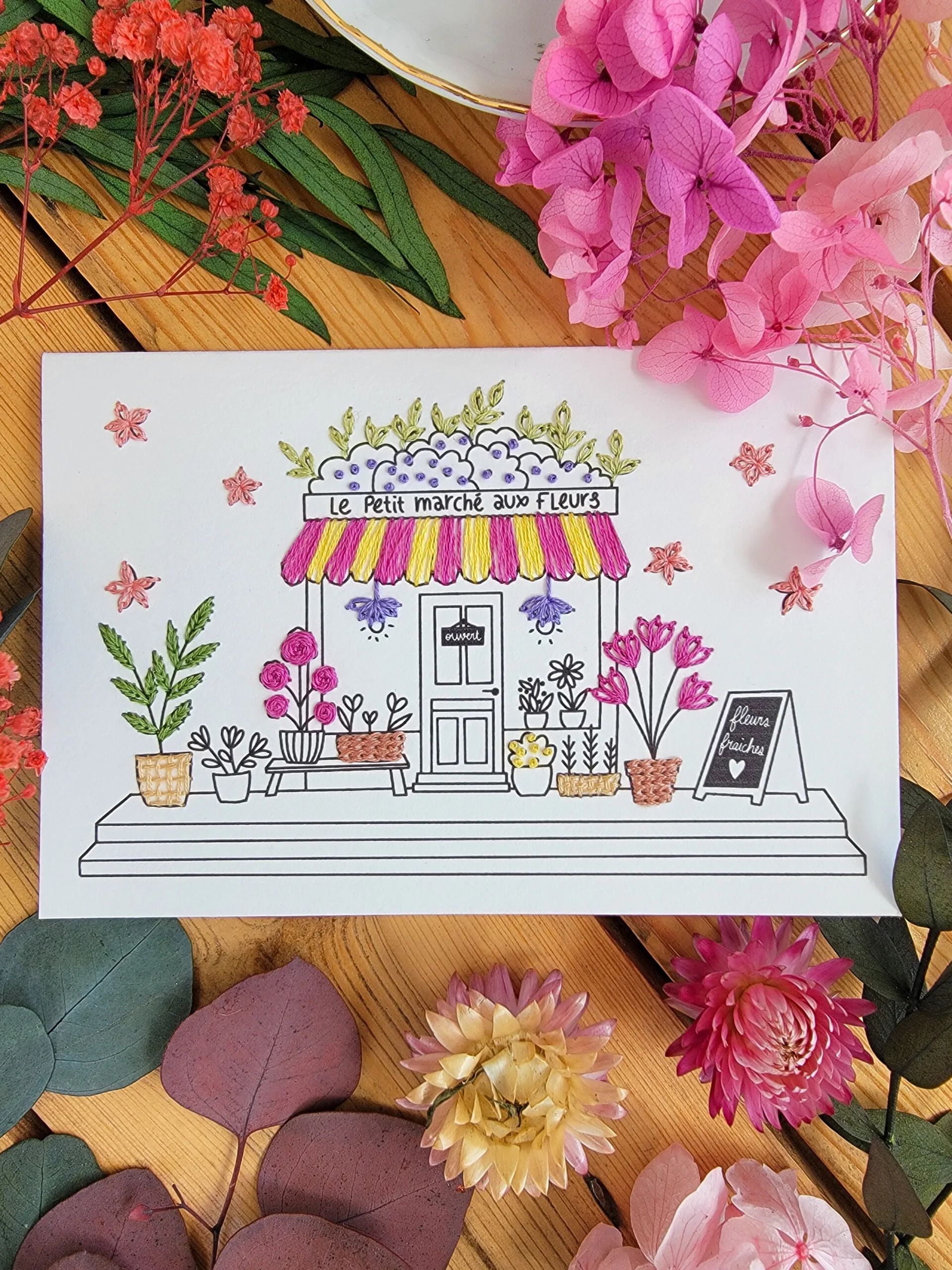 Carte à broder du petit marché aux fleurs avec son store retro et ses fleurs sur trottoir