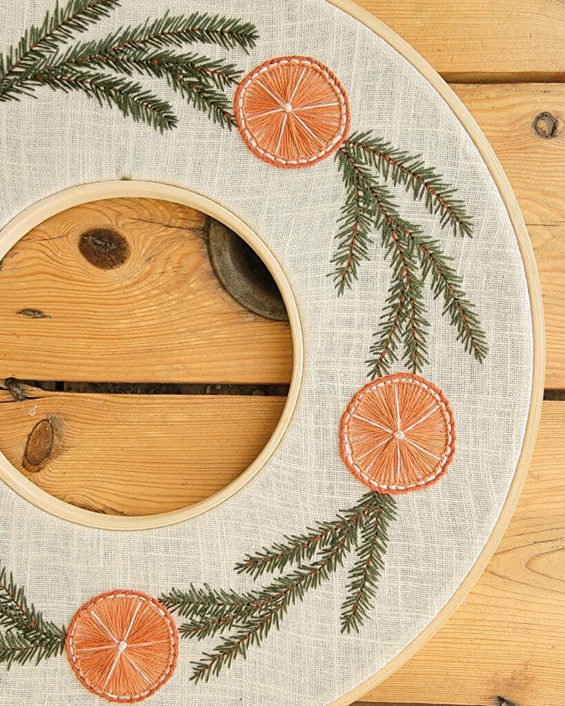 Idées cadeaux créatifs : Couronne de Noël brodée à la main représentant des branches de sapin et des oranges séchées